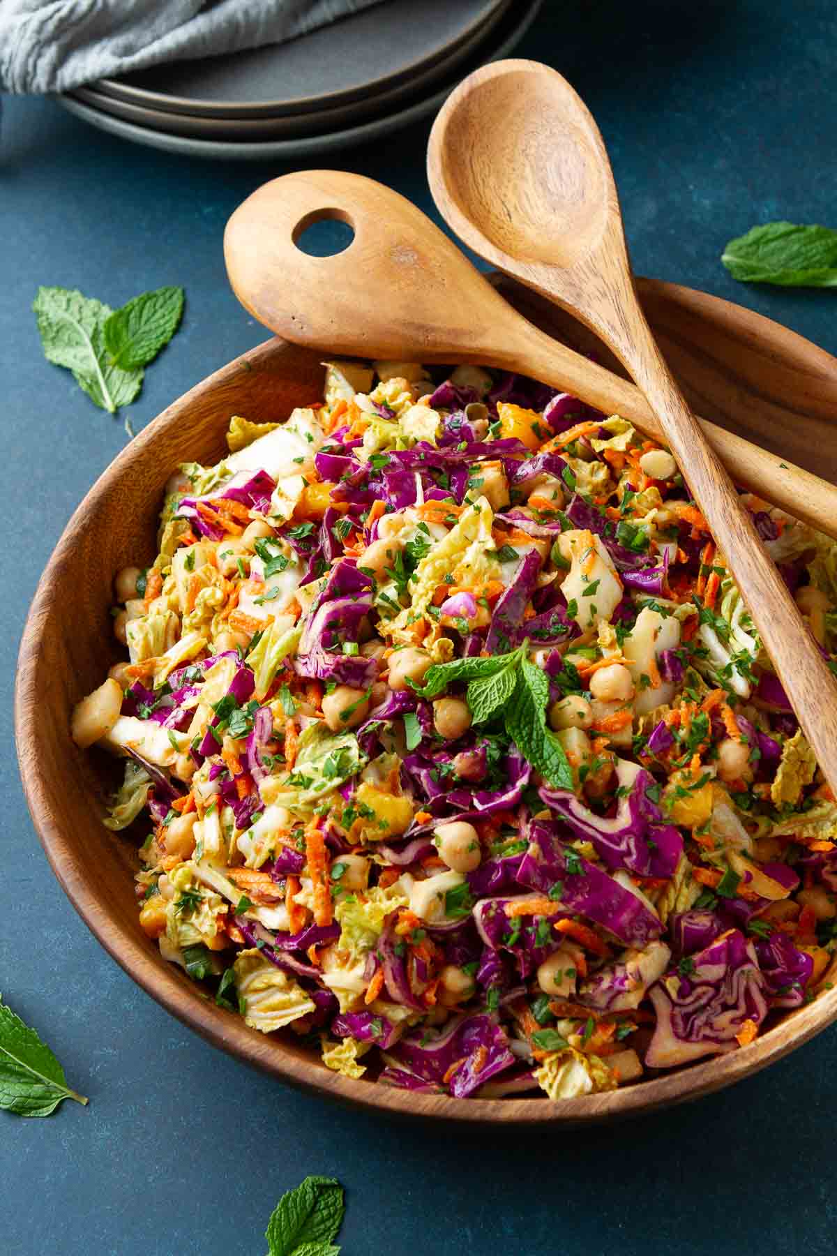 Cabbage and carrot slaw with chickpeas, mango and peanut dressing in a wooden salad bowl.