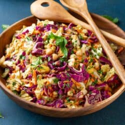 Slaw with chickpeas and peanut dressing in a large wooden salad bowl.