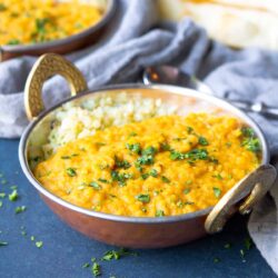 Red lentil dal and rice in a brass bowl.