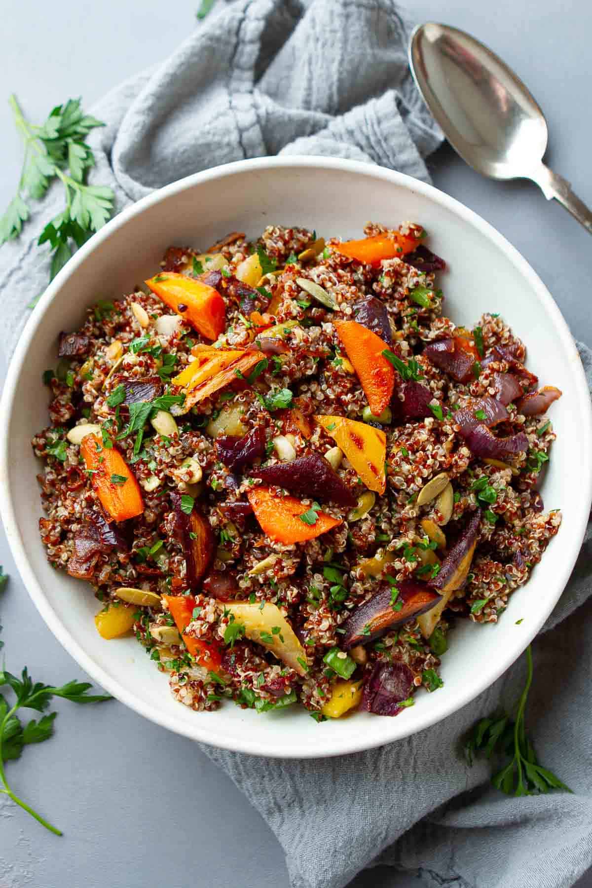 Quinoa salad with roasted carrots and onions in a white bowl.