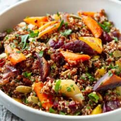 Tricolor quinoa salad with carrot and onions in a white bowl.