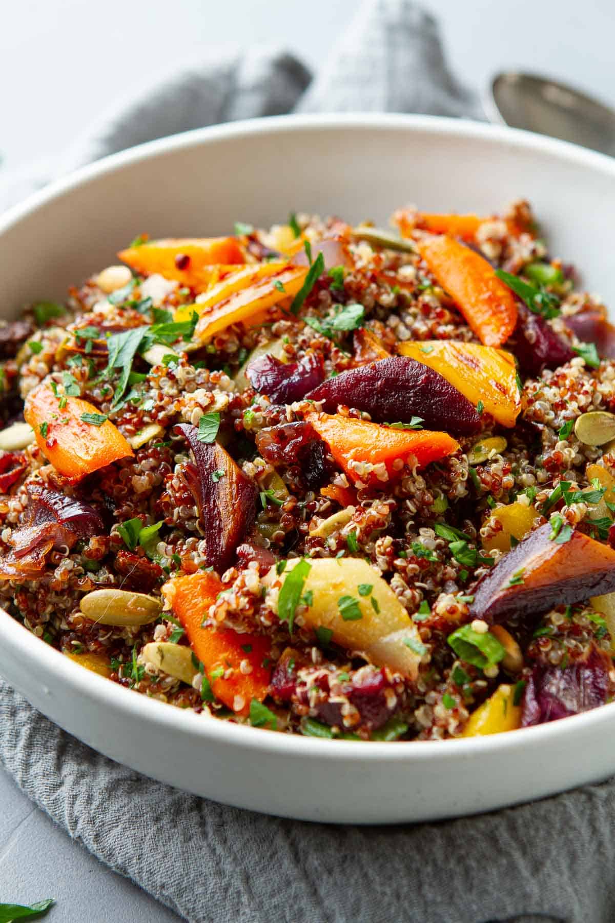 Tricolor quinoa salad with carrot and onions in a white bowl.