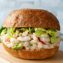 Shrimp salad sandwich with lettuce on a cutting board.