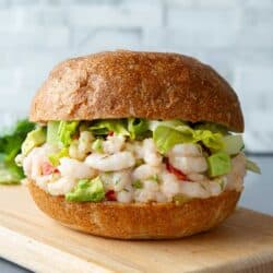 Shrimp salad sandwich with lettuce on a cutting board.