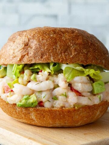 Shrimp salad sandwich with lettuce on a cutting board.