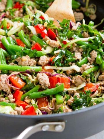 Stir-fry with ground turkey, green beans, bell peppers and cabbage in a skillet.