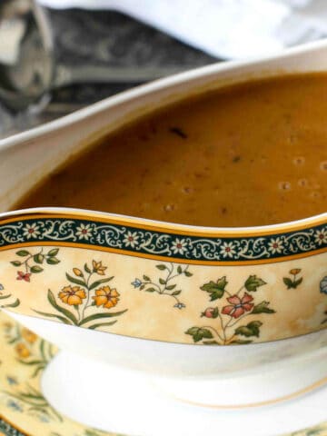 A white and yellow gravy boat filled with gravy.