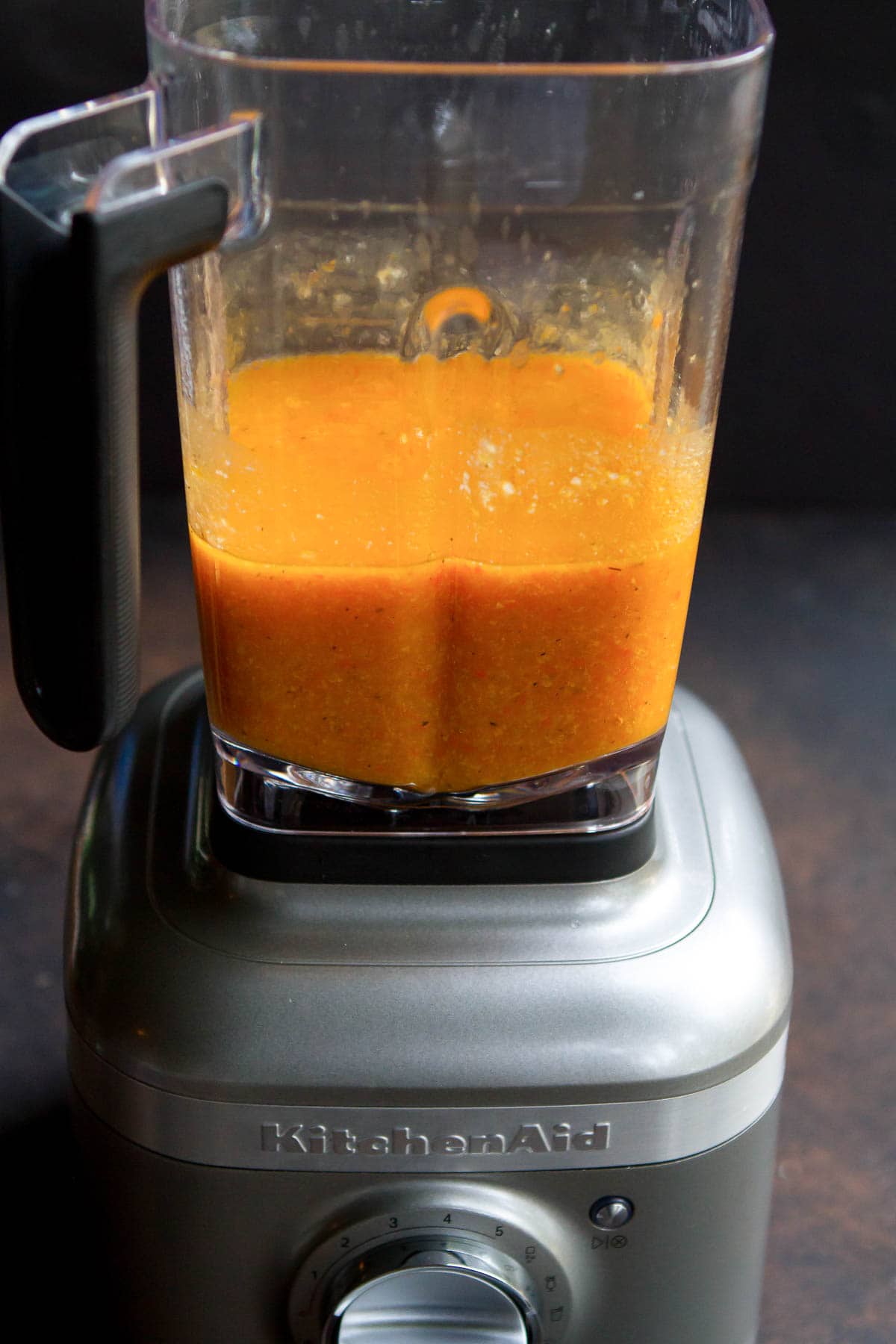 A blender half full of blended vegetable soup.