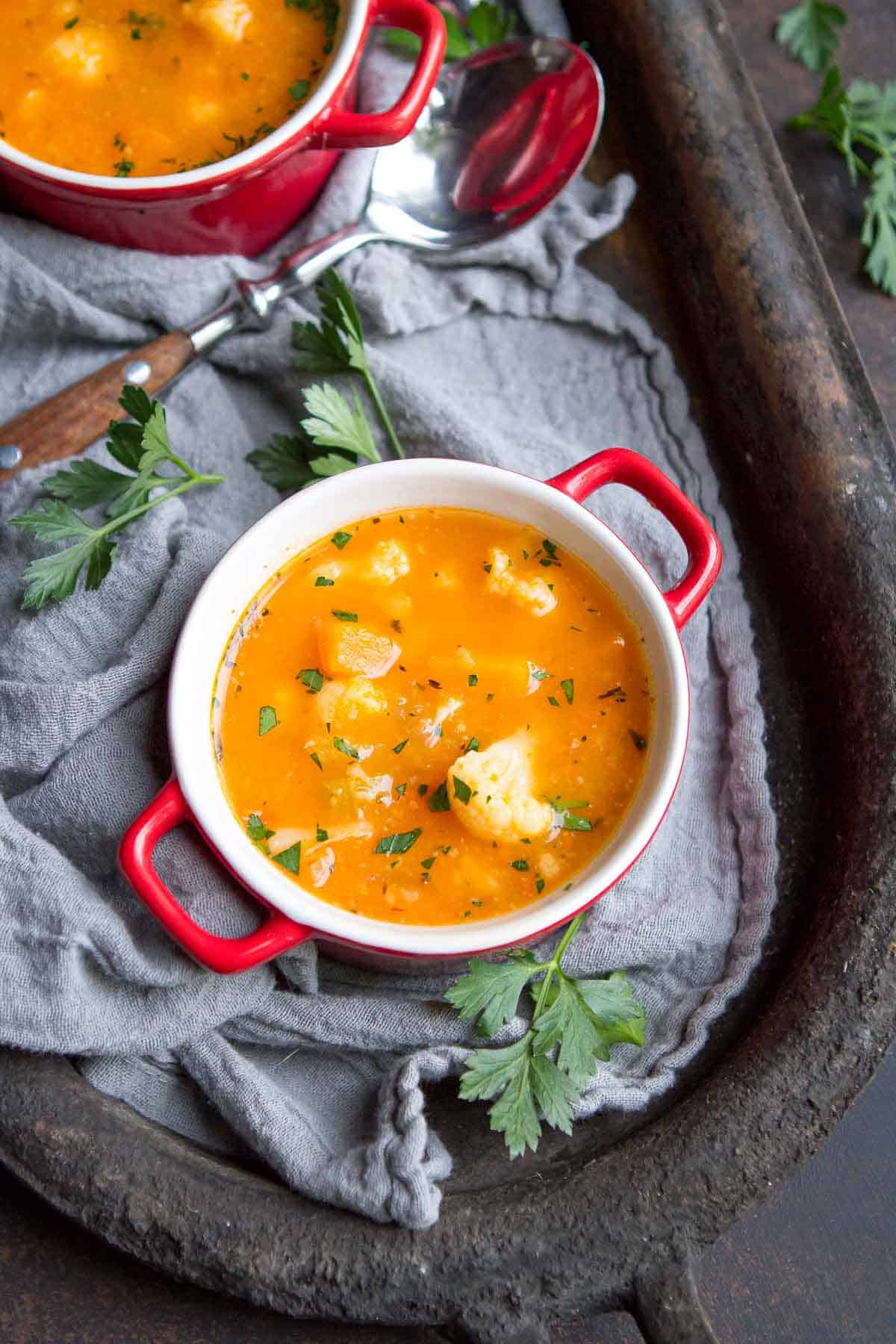 A small bowl of vegetable soup on a dark metal tray.