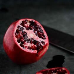 A whole pomegranate with a slice cut off.