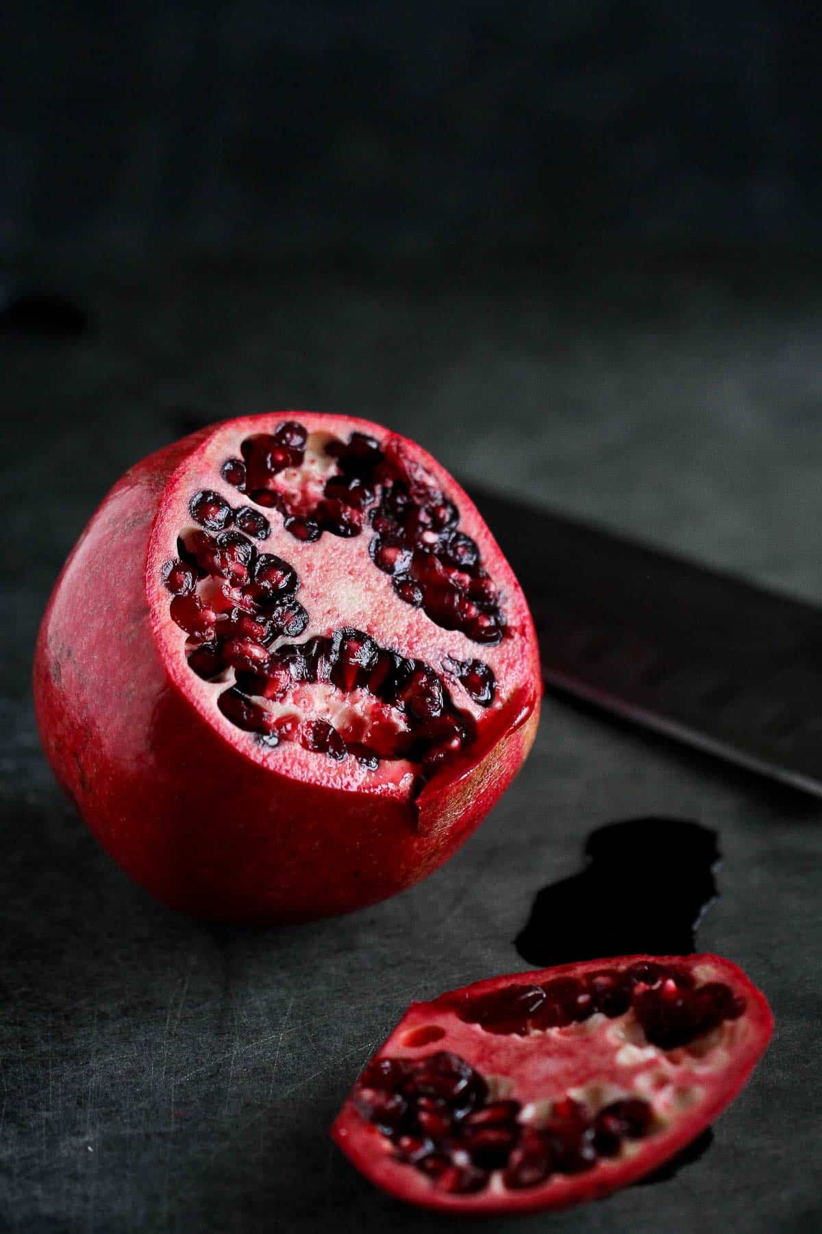 A whole pomegranate with a slice cut off.