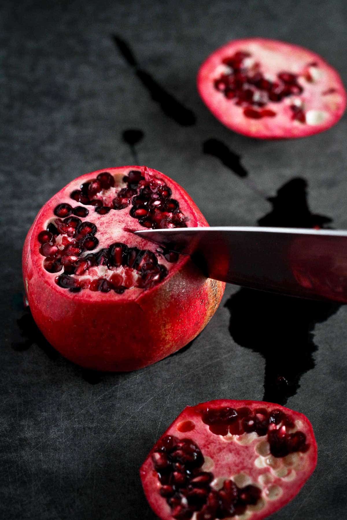 Slicing a pomegranate in sections with a chef's knife.