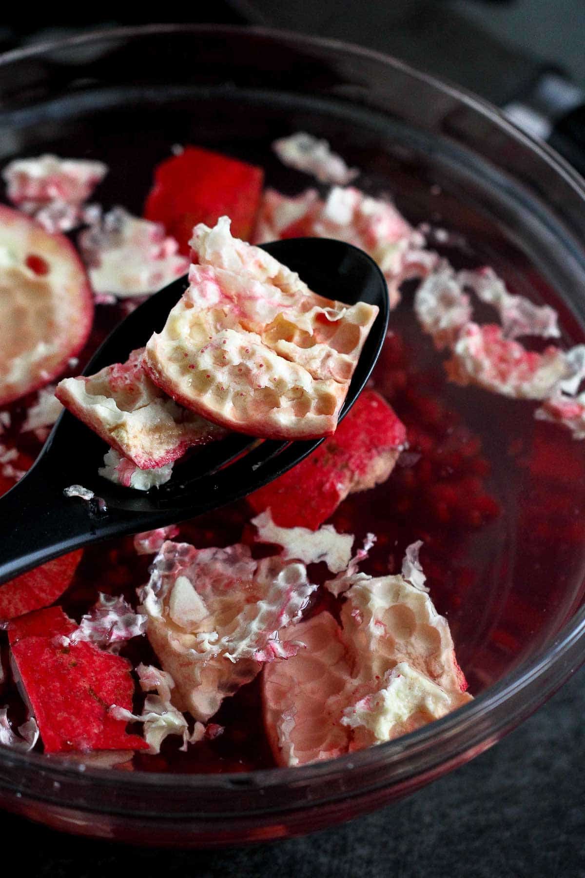 Scooping out pieces of pomegranate shell from a bowl of water.