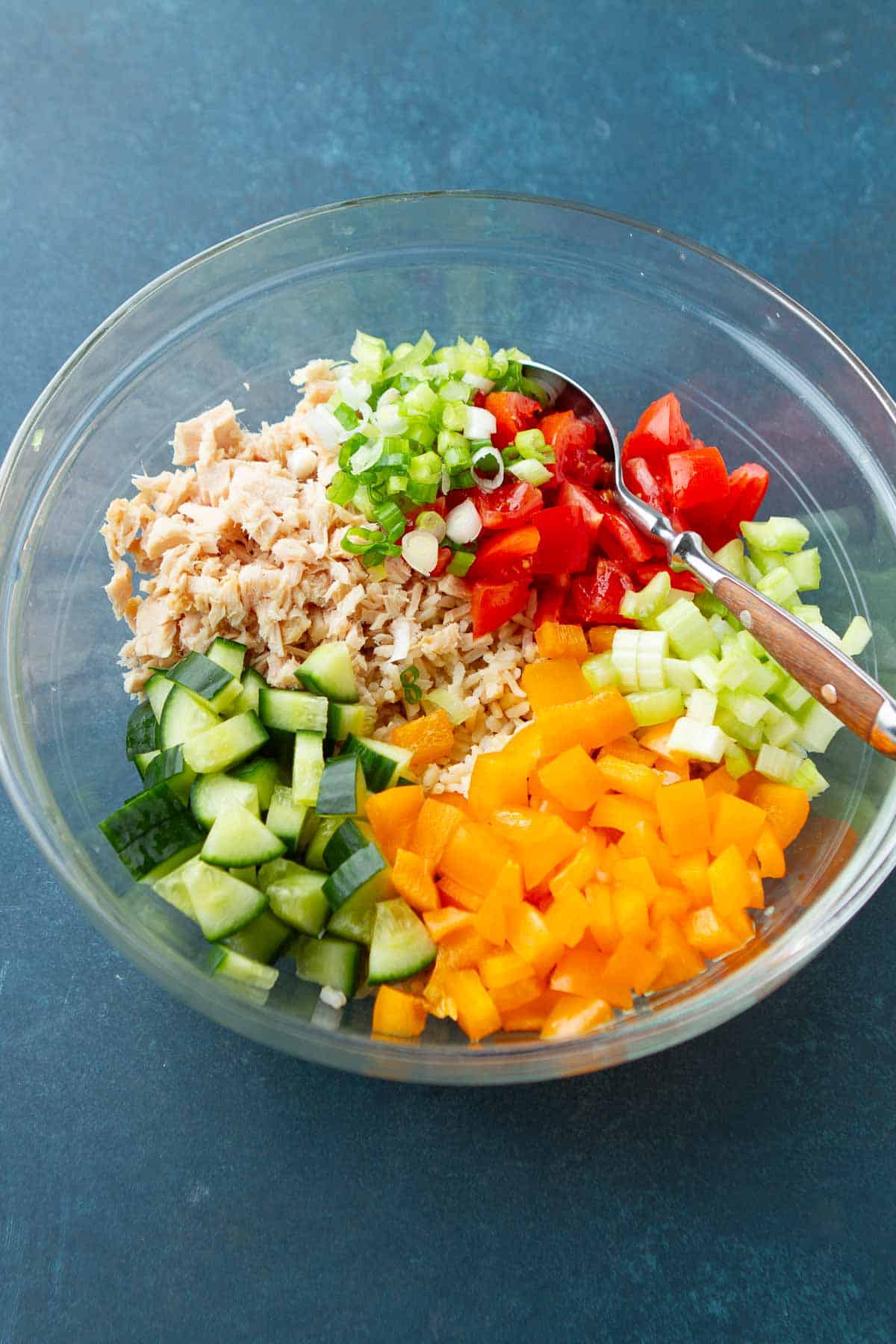 Canned tuna and chopped vegetables in a glass bowl.