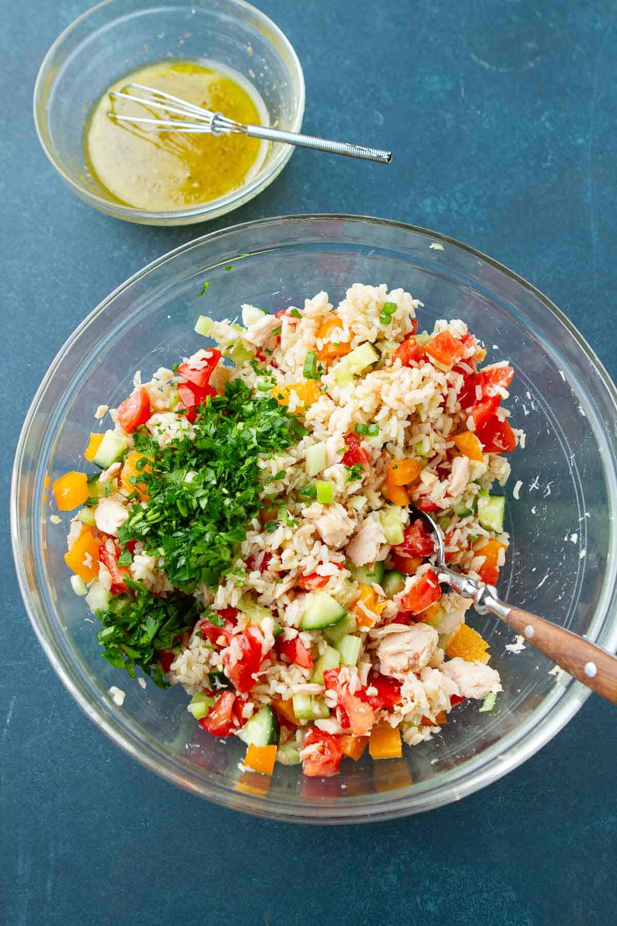 Rice, tuna and vegetables in a glass bowl, with a separate bowl of dressing.