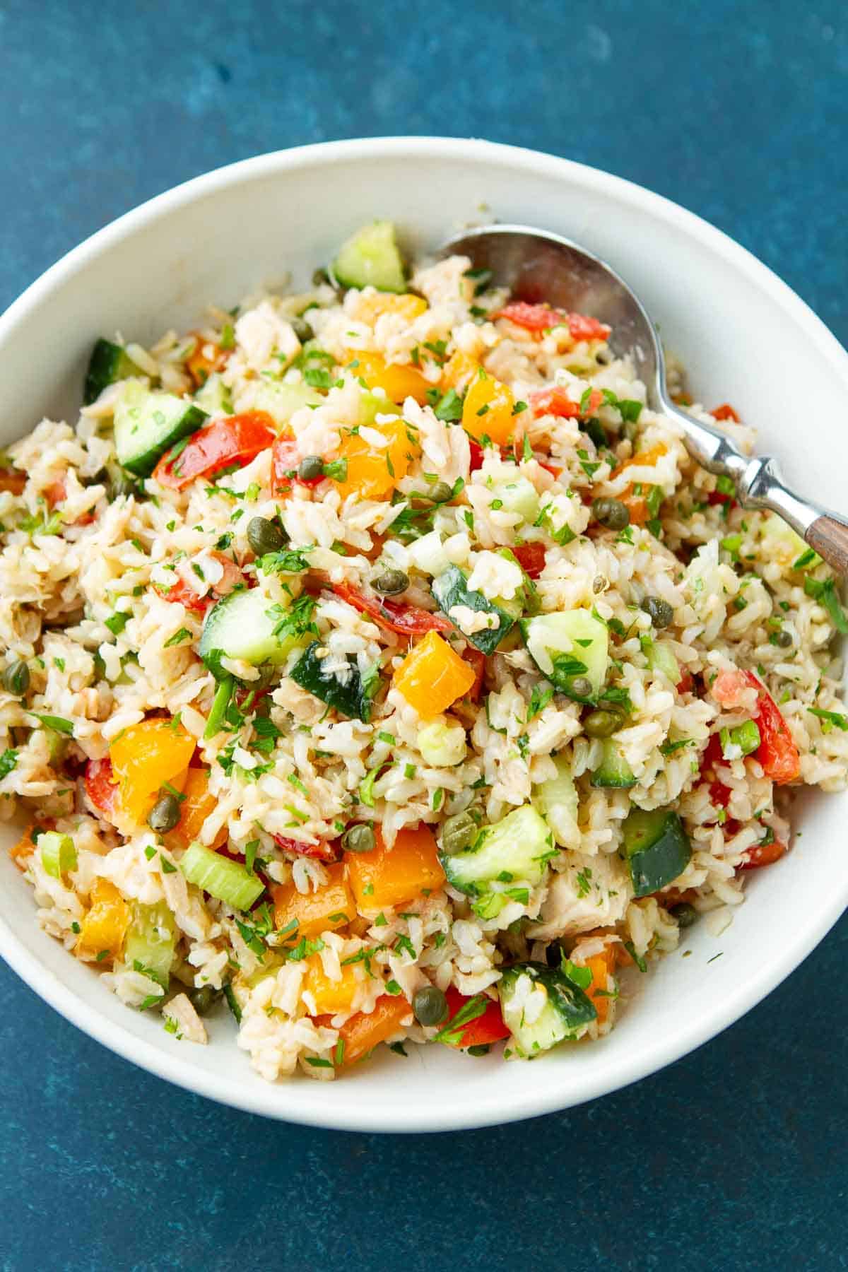 Tuna, vegetables and rice in a white bowl with a spoon.