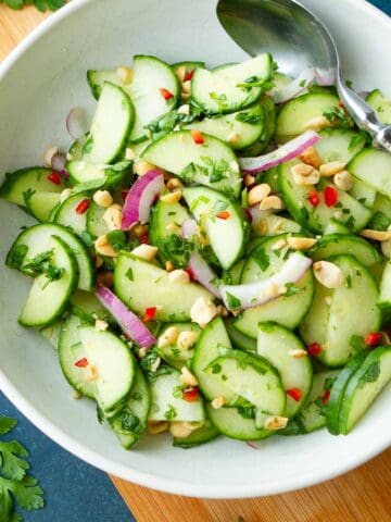 Thai cucumber salad and a spoon in a white bowl.