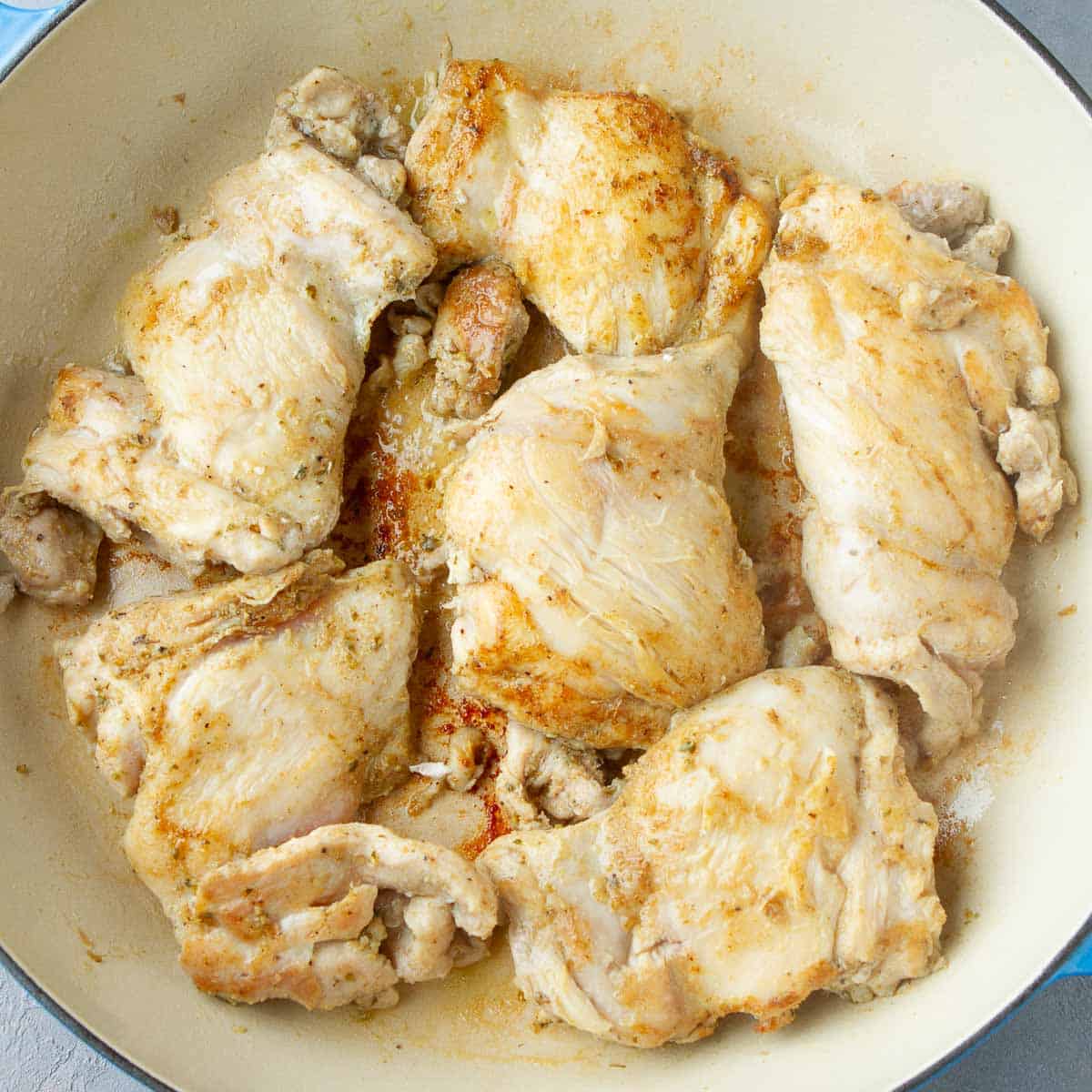 Cooked chicken thighs in a large skillet.