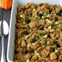 Bread stuffing with apples and cherries in a white baking dish.