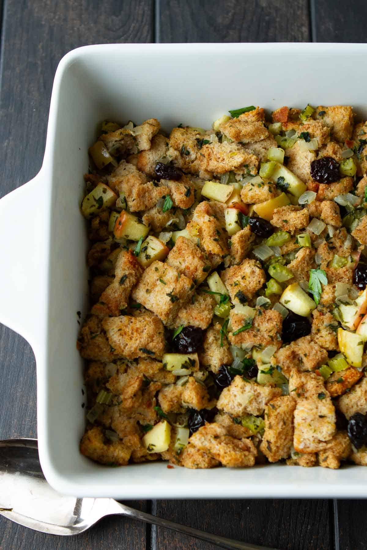 Herbed bread and apple stuffing in a white baking dish.