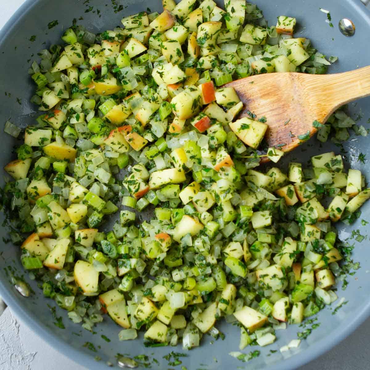 Chopped, sautéed celery and apples in a skillet.