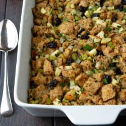 Bread stuffing with apples and cherries in a white baking dish.