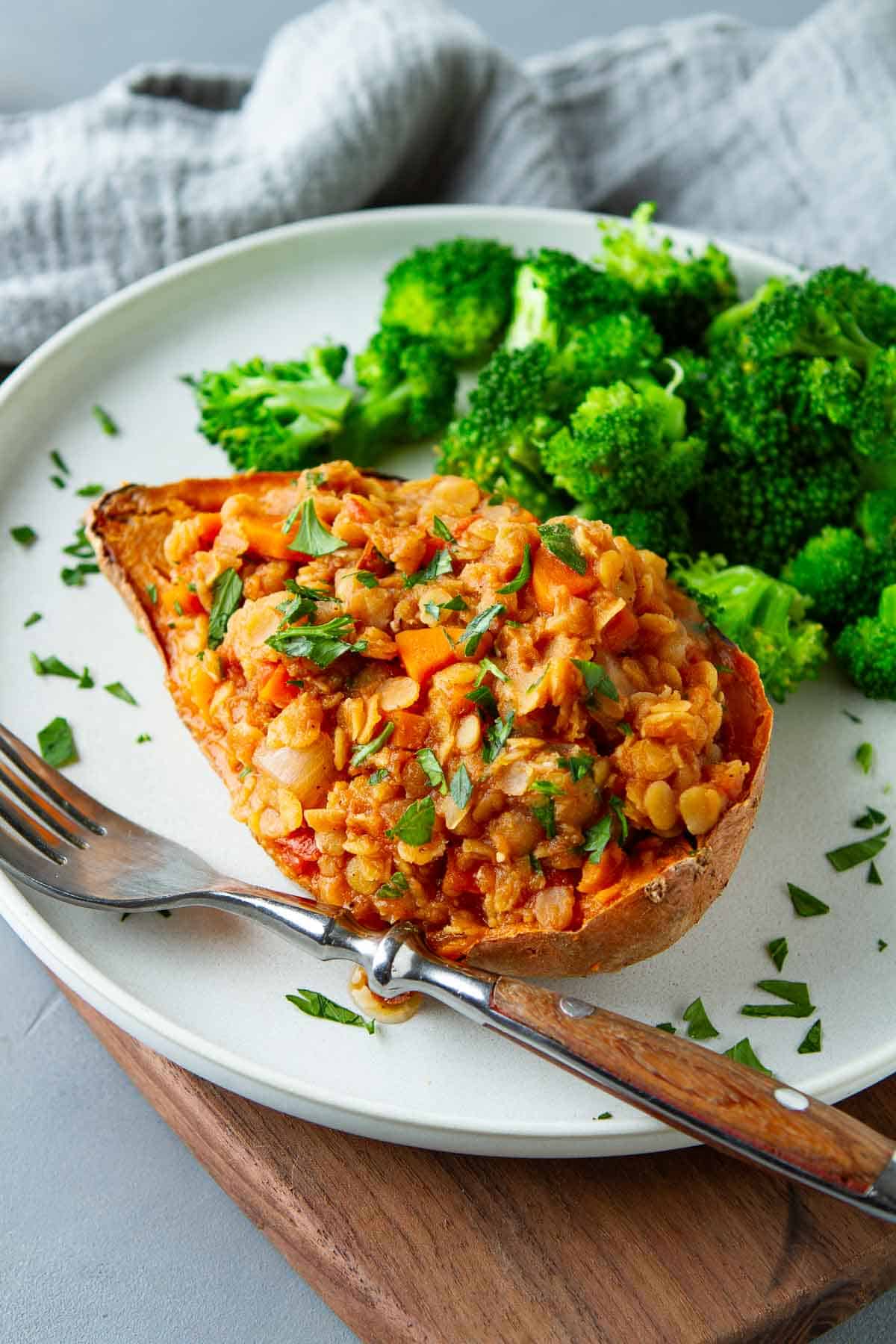 A sweet potato half stuffed with a lentil stew mixture, with broccoli on the side.