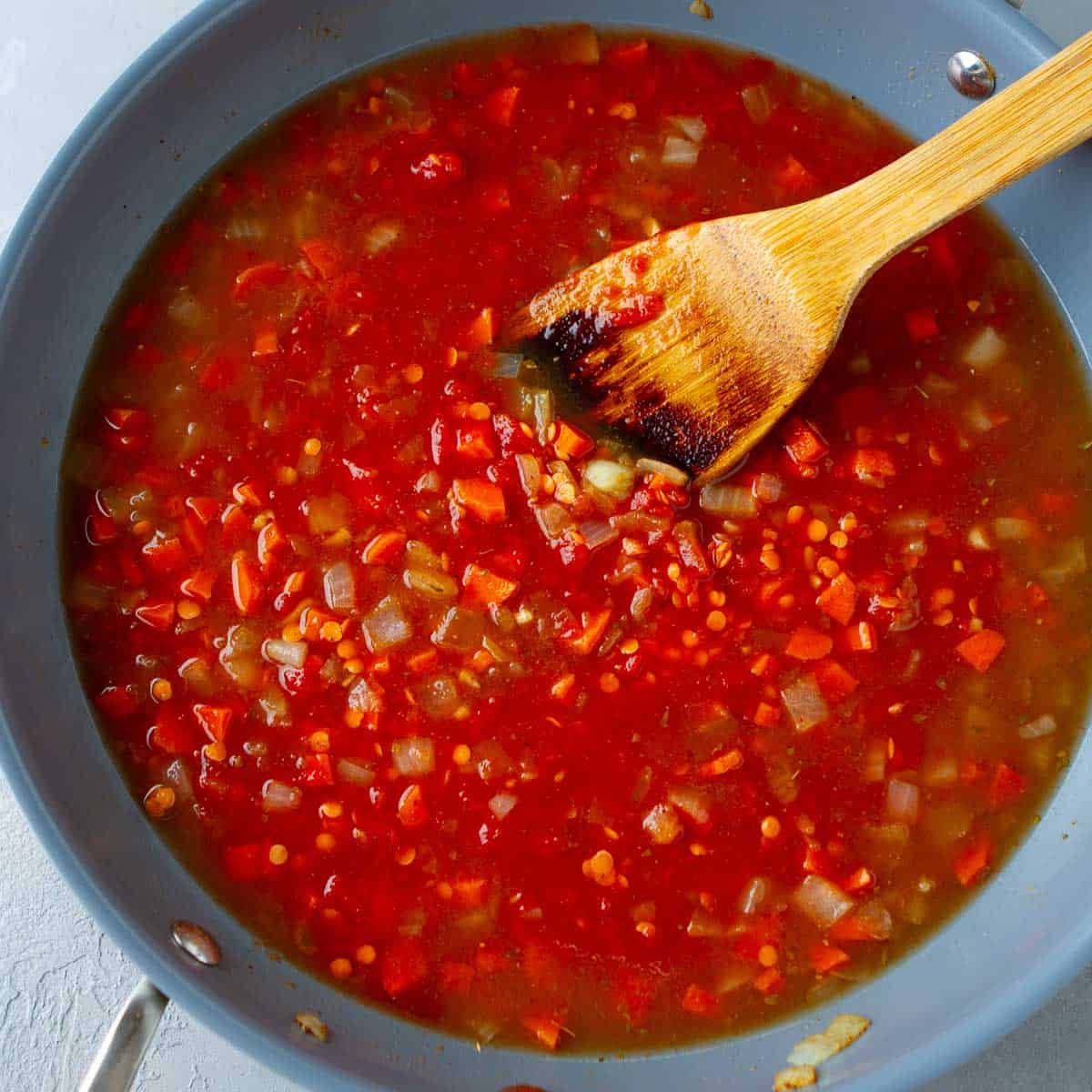 Crushed tomatoes, broth and vegetables in a skillet.