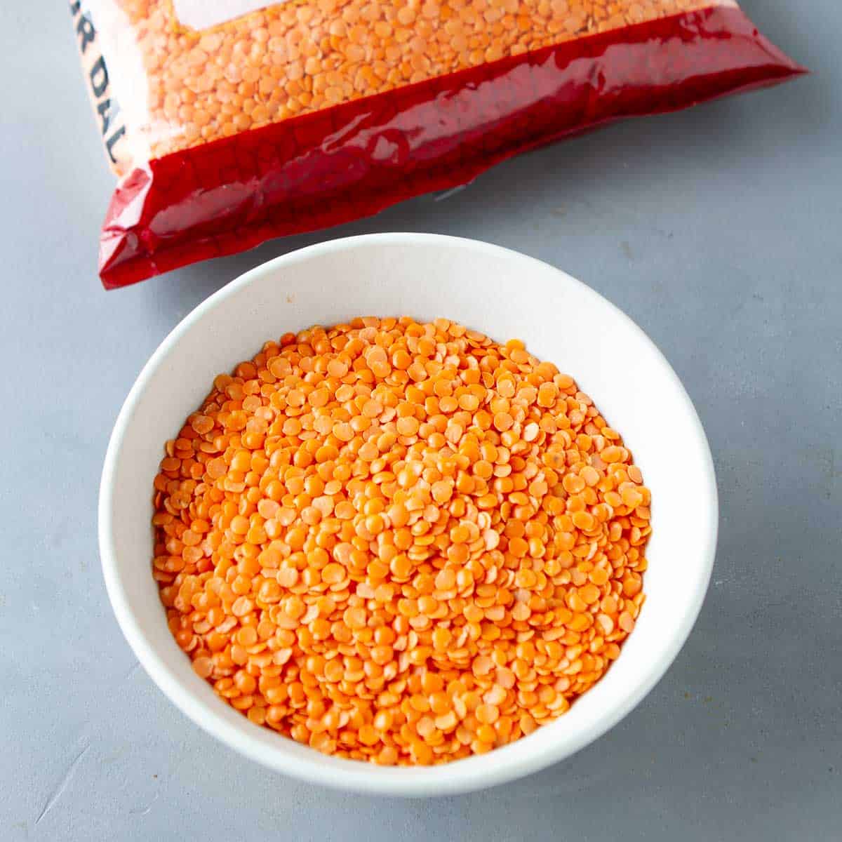 Dry red lentils in a white bowl.