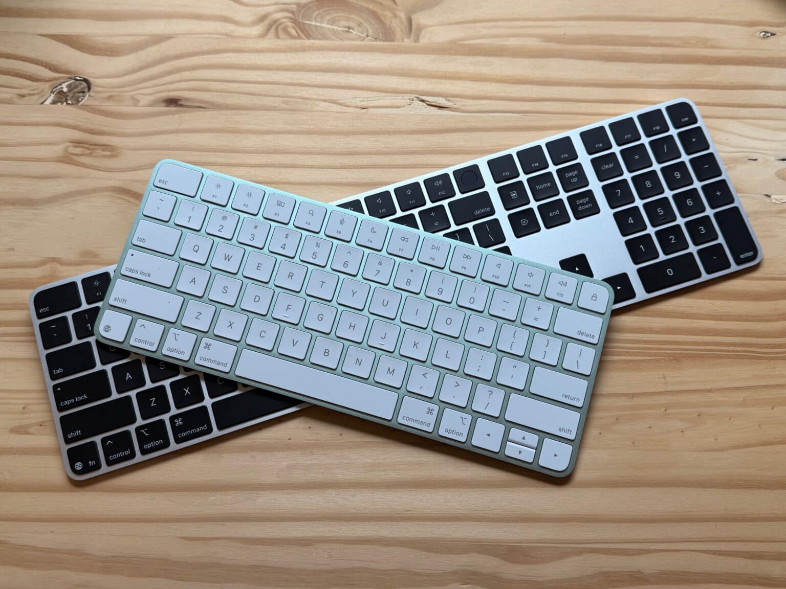 Green compact Magic Keyboard stacked on top of Black full-size Magic Keyboard.