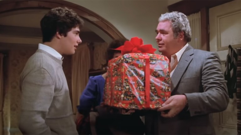 Screengrab of a boy receiving a wrapped Christmas gift from his father in Gremlins