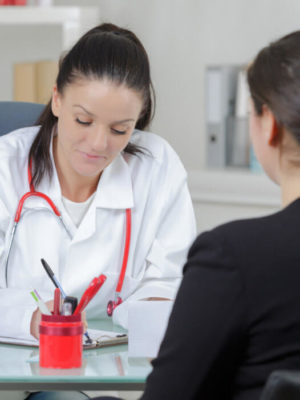 Doctor writing at desk with patient