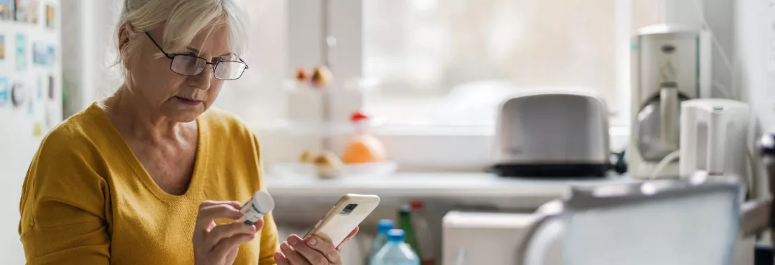 woman looking at a medicine and at her phone