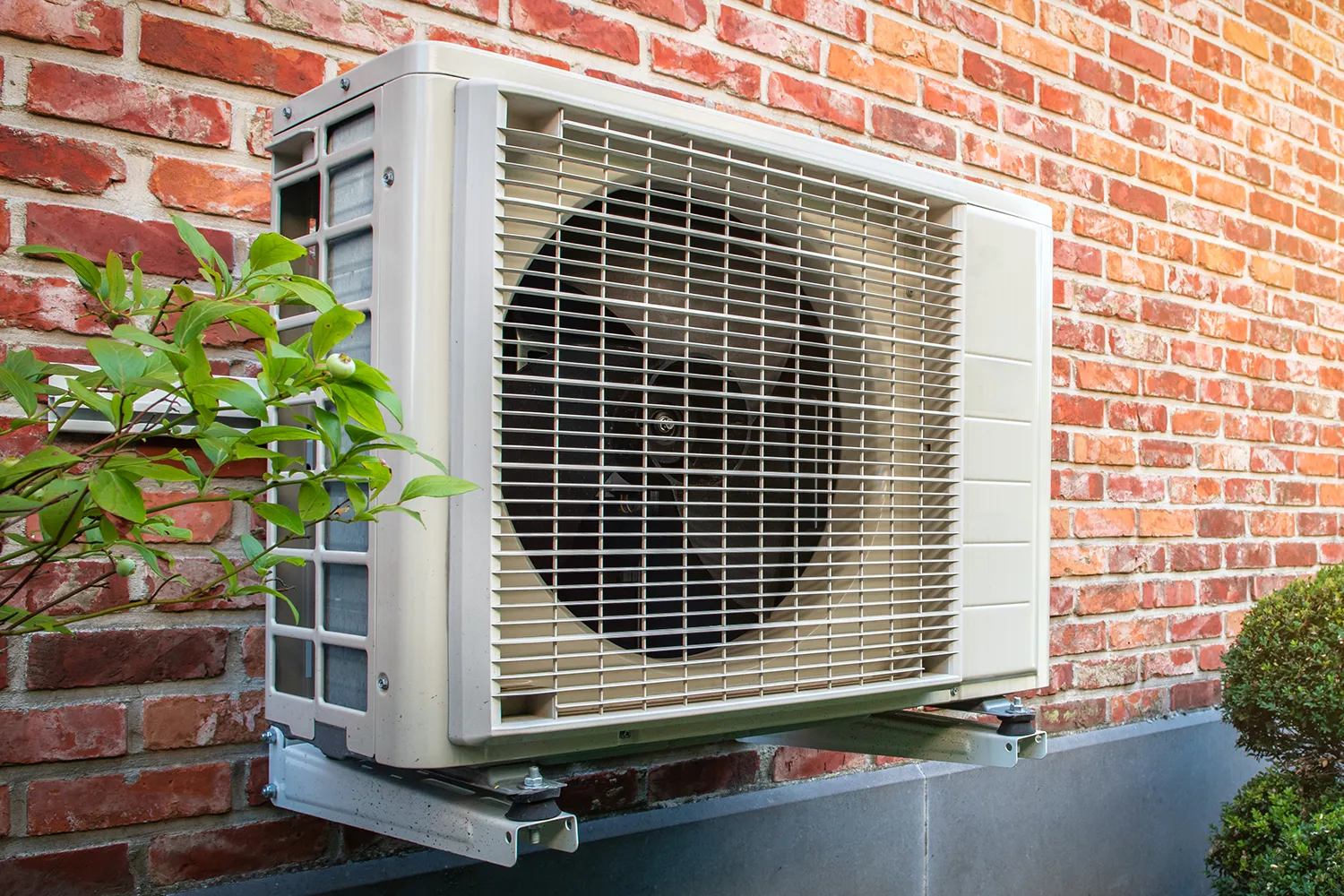 Air conditioning heat pump outdoor unit against brick wall