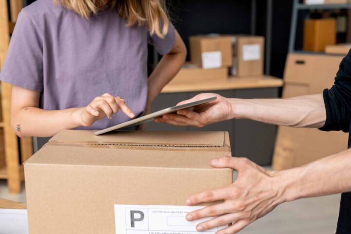 woman looking at a ipad whicle picking up a delivery box in a warehouse