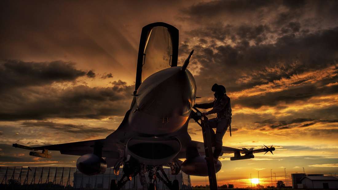 Eine F-16AM Fighting Falcon im Sonnenuntergang auf dem Rollfeld, während ein Pilot die Maschine besteigt.