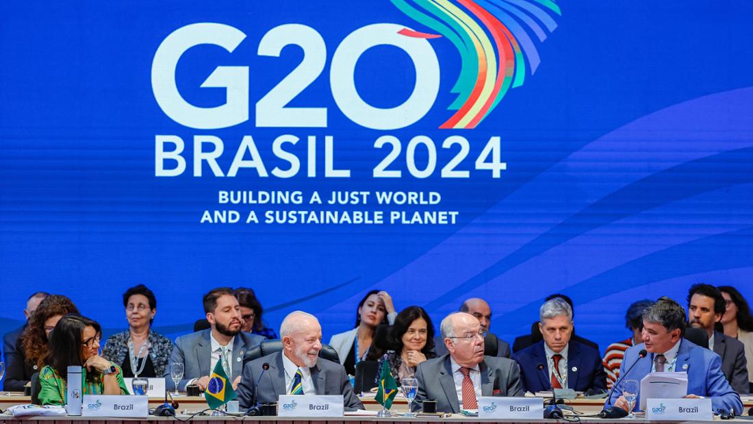 Brasiliens Präsident Lula sitzt auf einem Podium. Im Hintergrund ist das Logo des G20-Gipfels in Brasilien 2024 zu sehen. Darunter steht das Motto: „Aufbau einer gerechten Welt und eines nachhaltigen Planeten.“