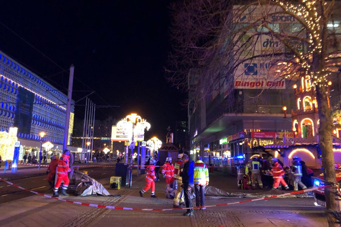 Einsatzkräfte von Rettungsdienst und Feuerwehr arbeiten hinter Absperrband auf dem Gelände des Weihnachtsmarkts in Magdeburg, nachdem bei einem Anschlag zwei Menschen gestorben und zahlreiche weitere verletzt worden sind.