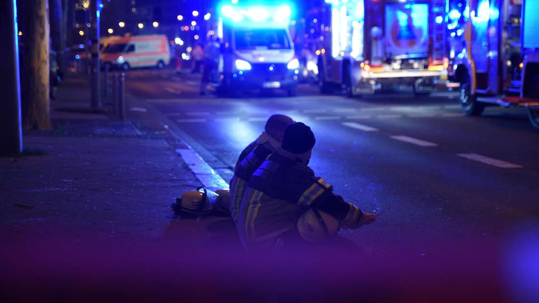 Einsatzkräfte sitzen beim Großeinsatz nach dem Anschlag auf dem Magdeburger Weihnachtsmarkt auf einem Bordstein.