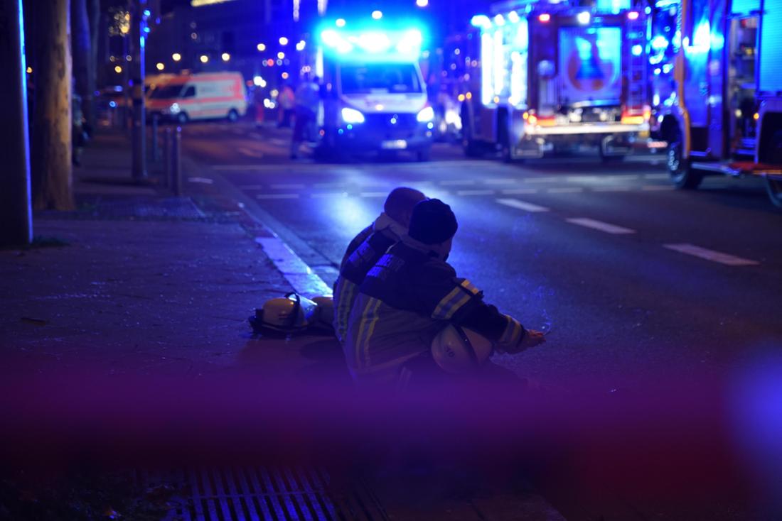 Einsatzkräfte sitzen beim Großeinsatz nach dem Anschlag auf dem Magdeburger Weihnachtsmarkt auf einem Bordstein.