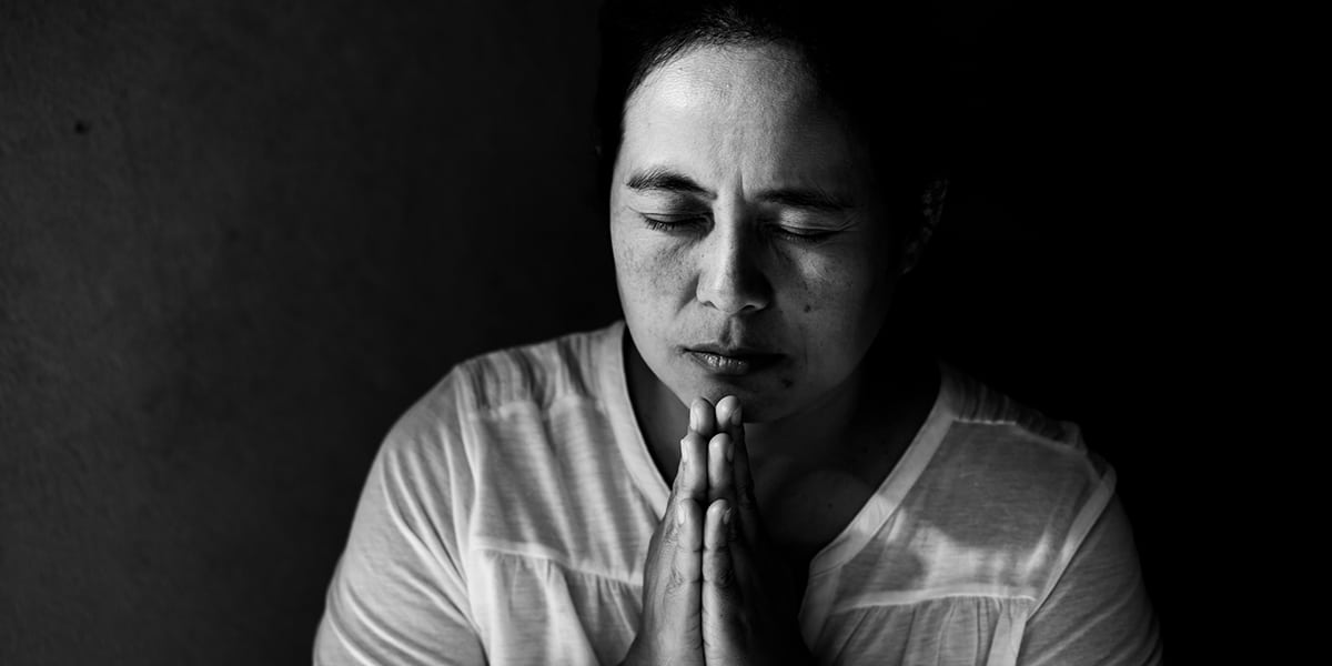 woman deep in prayer with hands folded.