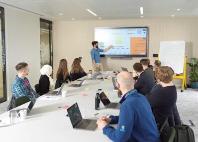 A person giving a presentation to a table full of people at a meeting.