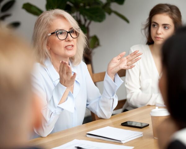 Older female speaking in meeting with colleagues