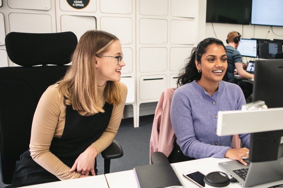 Two girls smiling together over work at Genomics England