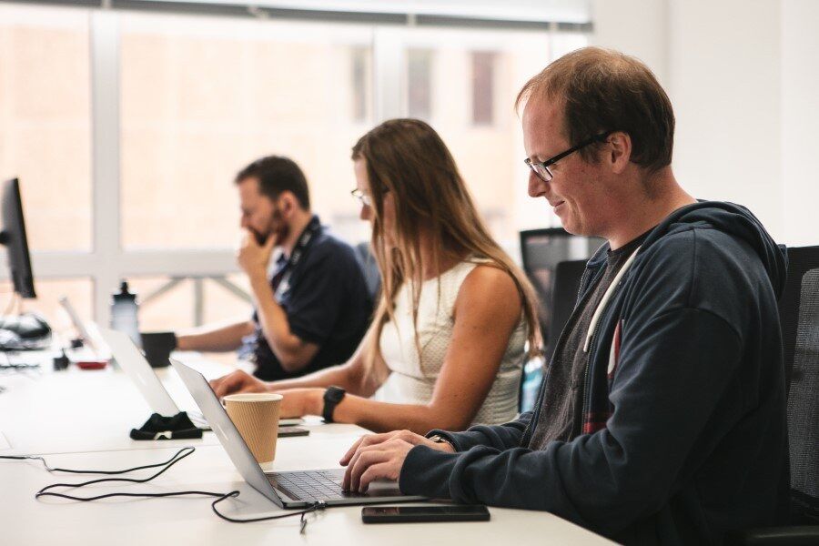 Three people hard at work on laptops at Genomics England