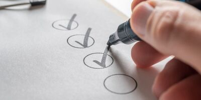 Person's hand checking a box on a sheet of paper