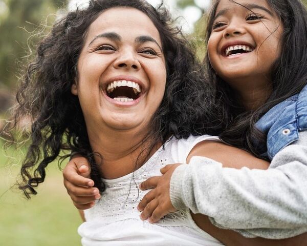 Daughter piggybacking on mother, laughing together