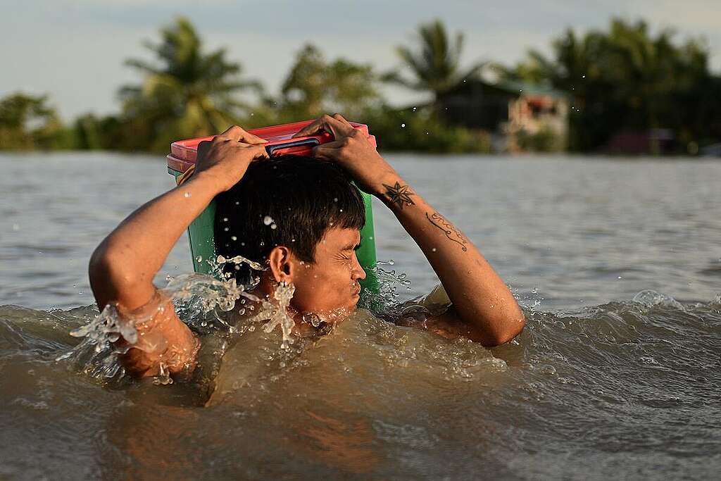 A man wades through a flooded street in Milaor in Naga City in Philippines. Several towns are still submerged in water brought by Severe Tropical storm Kristine (international name: Trami) in Camarines Sur. © Noel Celis / Greenpeace