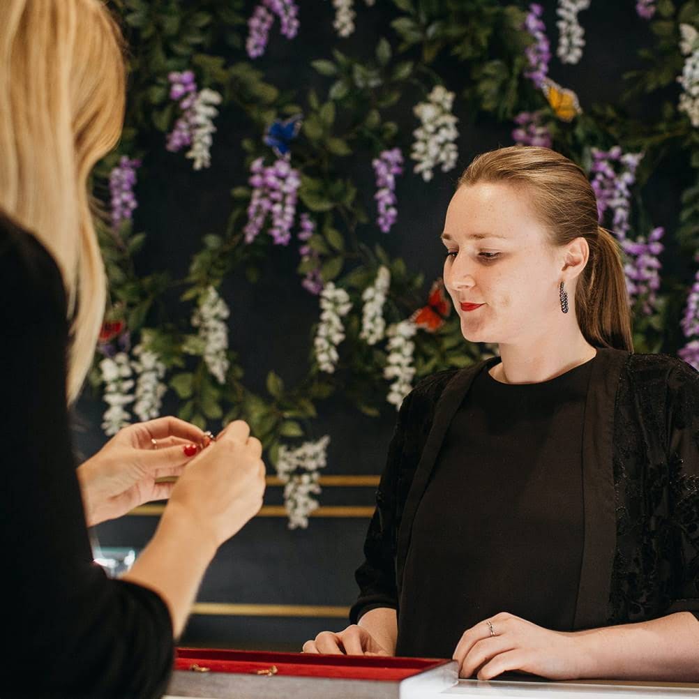 Employee of a jewelry store showing her products to a client.