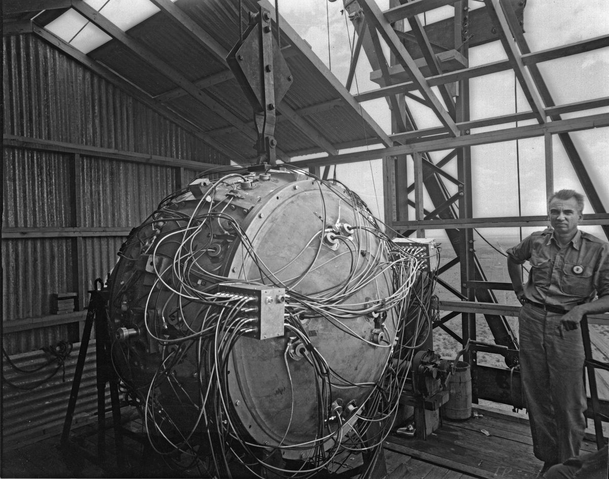 Norris Bradbury, group leader for bomb assembly, stands next to the partially assembled Gadget atop the test tower at Los Alamos in 1945. 